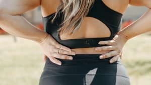 Close up image of female in activewear with hands on lower back