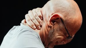 Person holding the back of their neck due to neck pain, illustrating whiplash or neck pain following a car accident.